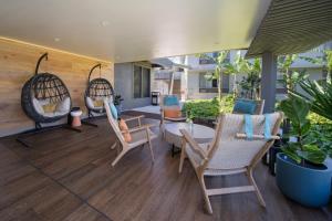 a patio with chairs and a table and swings at Maui Seaside Hotel in Kahului