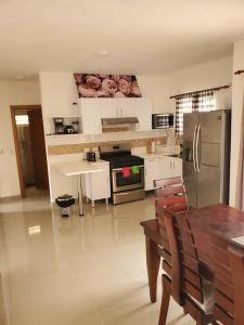 a kitchen with a stainless steel refrigerator and a table at Maison chaleureuse avec Jacuzzi ! in Punta Cana