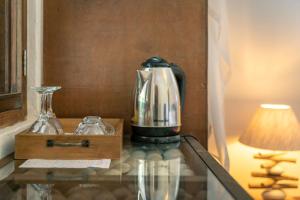 una macchinetta del caffè su un tavolo di vetro accanto a una lampada di Bliss Boutique Hotel Seychelles a Glacis
