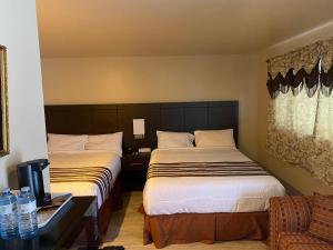 una habitación de hotel con 2 camas y una silla en Silver Maple Motel en Haliburton