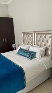 1 cama grande con cabecero de plata y almohadas blancas en Ikhwezi guest house en East London