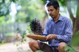 a man holding a wooden spoon with a bunch of bees at Bang Po Hut in Ban Bang Po