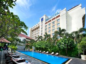 a hotel with a swimming pool in front of a building at Novotel Solo in Solo