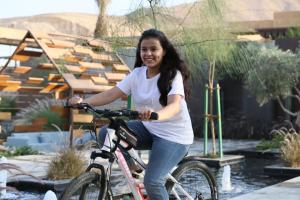 a woman riding a bike in a garden at Najdarah Resort in Riyadh