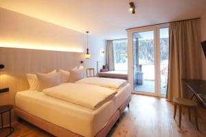a hotel room with a large bed and a balcony at Hotel die Arlbergerin ADULTS FRIENDLY 4 STAR in Sankt Anton am Arlberg