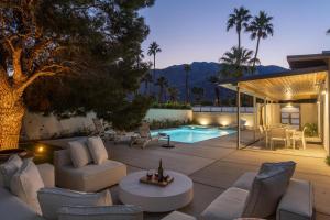 eine Terrasse mit weißen Möbeln und einem Pool in der Unterkunft Happy Hour in Palm Springs