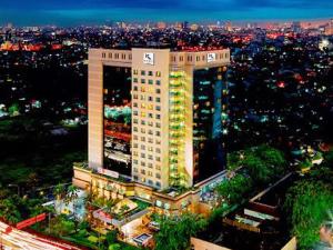 un edificio alto con luces encendidas en una ciudad por la noche en Hotel KIMAYA Slipi Jakarta By HARRIS en Yakarta