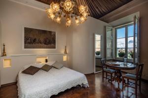 a bedroom with a bed and a table and a chandelier at La Dimora Dei Monaci in Siena