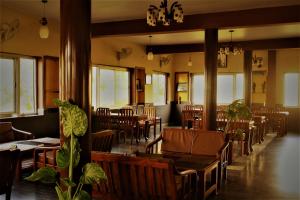 a dining room with tables and chairs and windows at Stupa Guest House in Bīr