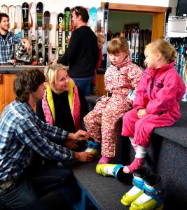 a man and two children sitting on a counter in a store at Hotel Pension Grimus in Mount Buller