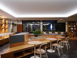 a library with wooden tables and stools at Hotel Etwas Tenjin in Fukuoka