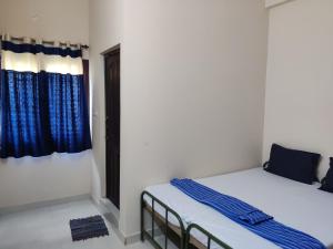 two beds in a room with blue curtains at Sundaram Rooms in Coimbatore