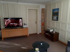 ein Wohnzimmer mit einem Flachbild-TV auf einer Kommode in der Unterkunft Ferienwohnung Rothorn Meiringen in Meiringen