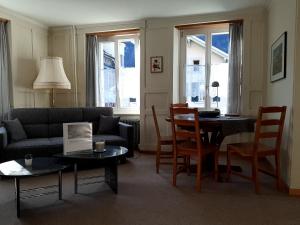 uma sala de estar com um sofá, uma mesa e cadeiras em Ferienwohnung Rothorn Meiringen em Meiringen