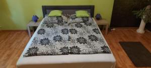 uma cama com um edredão preto e branco e almofadas verdes em Greenapartman em Budapeste