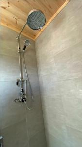 a shower with a shower head in a bathroom at Beautiful Wooden tiny house, Glamping cabin with hot tub 3 in Tuxford