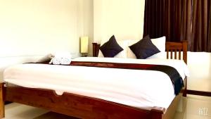 a bedroom with a large bed with white sheets and blue pillows at EZ House in Sukhothai