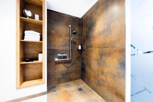 ein Bad mit einer Dusche und einer Holzwand in der Unterkunft Hochwald Lodge in Morbach