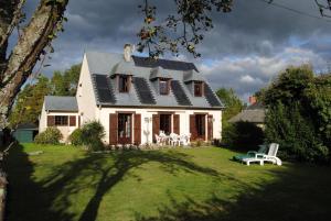 una grande casa bianca con tetto e cortile di Maison de vacances a Trévières