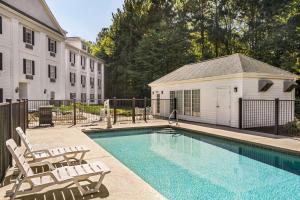 a swimming pool with chairs and a house at Baymont by Wyndham Henderson Oxford in Henderson