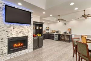 a living room with a fireplace and a television on a wall at Baymont by Wyndham Henderson Oxford in Henderson