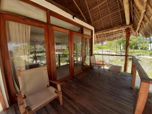 a porch of a house with chairs and windows at Jaribu Beach Hotel in Paje