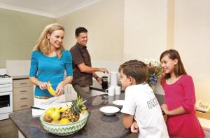 Une femme debout dans une cuisine avec un groupe de personnes dans l'établissement Oxley Court Serviced Apartments, à Canberra