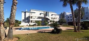 un grand bâtiment blanc avec une piscine et des palmiers dans l'établissement Oasis Hoyo 12 - Oliva Nova playa MET&GOLF, à Oliva