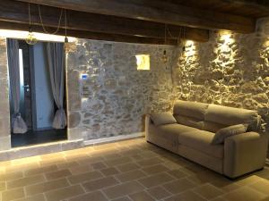 een woonkamer met een bank en een stenen muur bij Le dimore nel borgo in Pescocostanzo