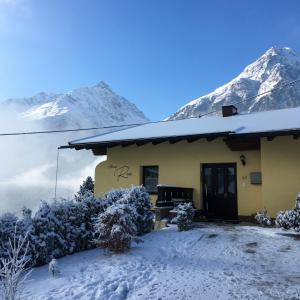ein schneebedecktes Haus mit Bergen im Hintergrund in der Unterkunft Haus Resi in Längenfeld