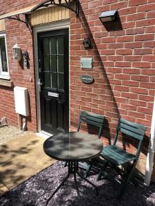 a table and two chairs next to a brick building at Abbotsleigh Rest - close to Glastonbury Abbey in Glastonbury