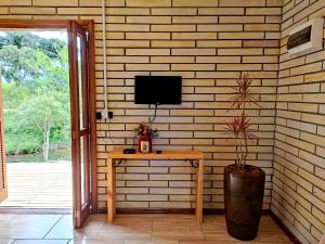 ein Raum mit einem Tisch und einem Fernseher an der Wand in der Unterkunft Sítio da Figueira in Praia Grande