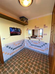 a bathroom with blue tiles and a tv on the wall at Bilocale condominio del sole in San Giacomo