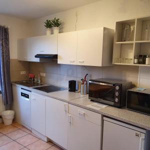 a kitchen with white cabinets and a microwave at NiceRooms Aachen in Würselen