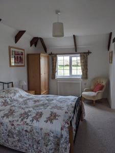 a bedroom with a bed and a chair and a window at The Cottage, Little Trembroath in Stithians