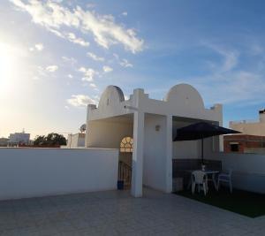Nice Holiday Apartment Hammam Sousse في حمام سوسة: مبنى ابيض بطاوله ومظله