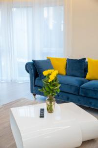 a living room with a blue couch and a vase with yellow flowers at Luxurious Blue&Yellow Apartment in Kaunas Center in Kaunas