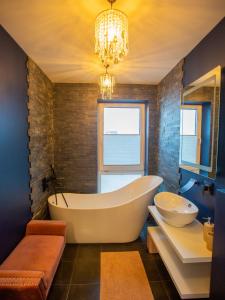 a bathroom with a tub and a sink and a chandelier at Luxurious Blue&Yellow Apartment in Kaunas Center in Kaunas