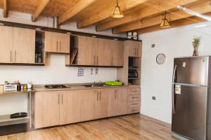 uma cozinha com armários de madeira e um frigorífico de aço inoxidável em Hostal Tulvak Atacama em San Pedro de Atacama