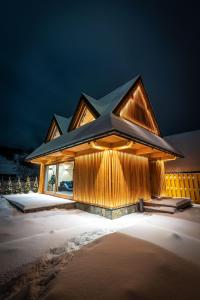 una casa con una fachada iluminada en la nieve en Górska Baja Premium House, en Witów