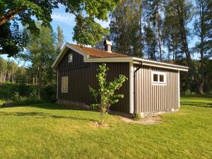 ein kleiner Schuppen in einem Hof mit einem Baum in der Unterkunft Kilsborgs Gård - Lakehouse in Svanskog