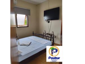 a bedroom with a bed with a tv on the wall at Poutur Pousada in Maceió