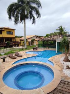 a large swimming pool in a yard with palm trees at Pousada Coração de Búzios in Búzios