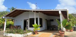 una pequeña casa blanca con plantas delante en Playa Tranquilo B&B and Dive Shop, en San Andrés