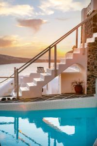 a house with a swimming pool and stairs next to the water at Oia Mare Villas in Oia
