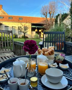 uma mesa com pequeno-almoço de café e croissants em La Planque - Chambres avec Jacuzzi em Fleury-en-Bière