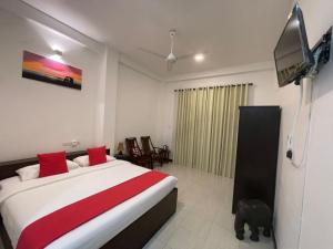 a bedroom with a bed and a tv on the wall at KITHULA Boutique Hotel in Hikkaduwa