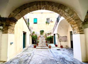 une arche dans une ruelle avec des escaliers dans un bâtiment dans l'établissement Cortile Umberto I, à Cefalù
