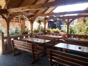 a patio with wooden tables and benches in a restaurant at Pensiunea Poiana in Borşa