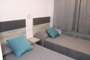 - une chambre avec 2 lits dotés d'oreillers bleus dans l'établissement APARTAMENTOS AGUAMARINA, à Peñíscola